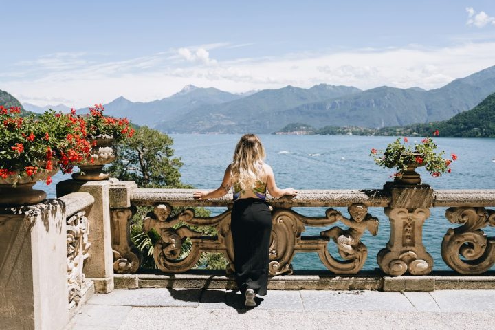 A woman is sitting on a balcony overlooking the water